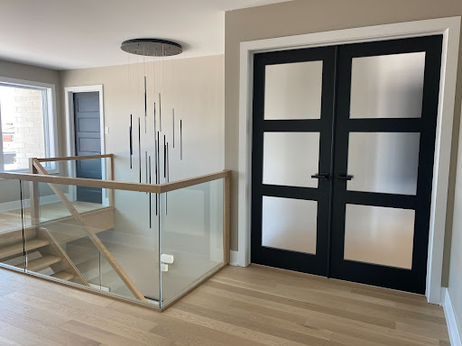 Porte vitrée noire avec vitre givrée planché de bois et cage d'escalier en vitre